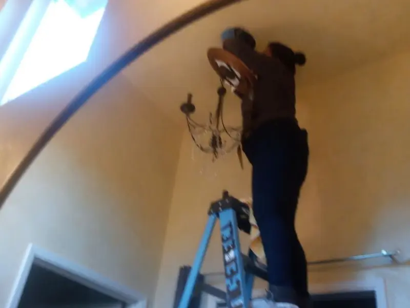 Electrician installing a chandelier in a Carlisle residence